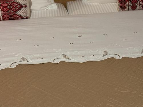 a bed with a white bedspread with birds on it at Mezini Guest House in Gjirokastër