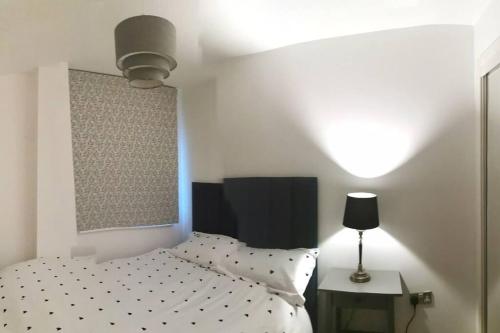 a bedroom with a bed and a lamp next to a table at Waterfront Apartment in Cardiff