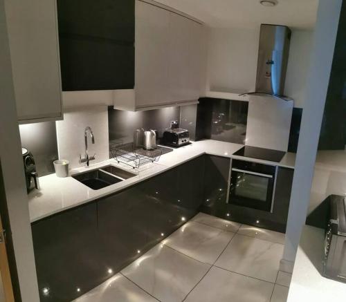 a kitchen with white counter tops and appliances at Waterfront Apartment in Cardiff