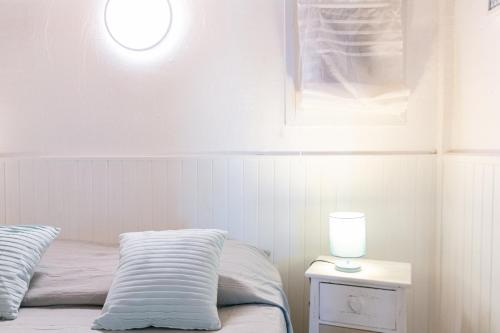 une chambre avec un lit et une table avec une lampe dans l'établissement Le Cigalou, authentique cabanon de pêcheur en bord de mer avec sa terrasse spacieuse et aménagée, à Hyères