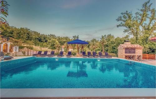 a swimming pool with chairs and a blue umbrella at Nice Home In Bribir With Sauna in Bribir