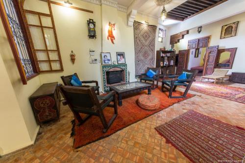a living room with chairs and a fireplace at Ryad Bahia in Meknès