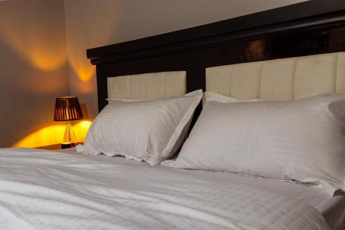 a white bed with white pillows and a black headboard at Matinza Homes, Makerere - 10min Drive to KLA City in Kampala