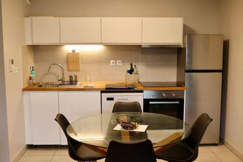 une cuisine avec une table en verre et des chaises noires dans l'établissement Le Copenhague - Parking privé, à Arras