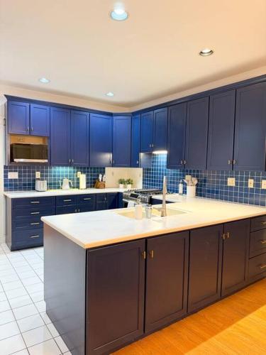 a large kitchen with blue cabinets and a sink at Cozy Ithaca Retreat - Fenced Yard - 7 min to Cornell in Ithaca