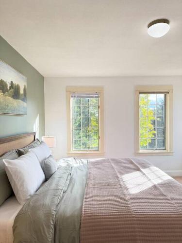 a bedroom with a large bed with two windows at Cozy Ithaca Retreat - Fenced Yard - 7 min to Cornell in Ithaca