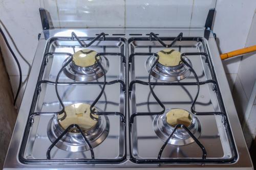 a stove top oven with four pots and pans at Matinza Homes, Makerere - 10min Drive to KLA City in Kampala