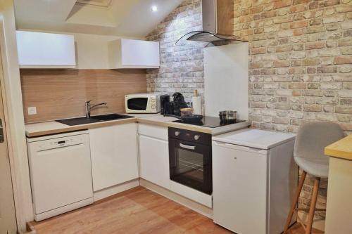 una cucina con elettrodomestici bianchi e un muro di mattoni di Appartement T2 proche gare et centre ville a Châteauroux
