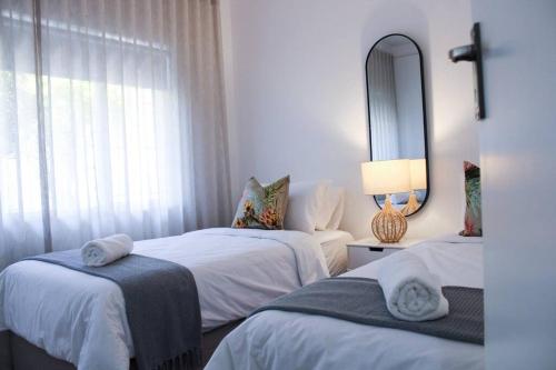 a bedroom with two beds and a mirror at Luxury Poolside Villa Irene in Cape Town