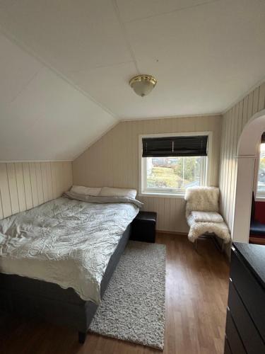 a bedroom with a bed and a chair and a window at Nydelige Tromsdalen - rom i enebolig in Tromsø