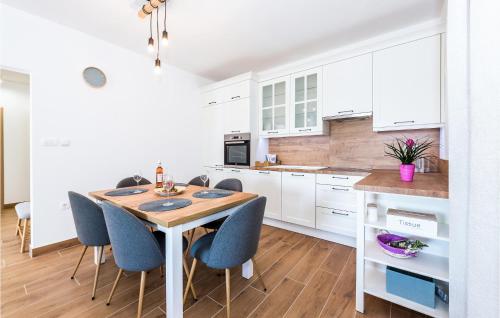 une cuisine avec des armoires blanches et une table et des chaises en bois dans l'établissement Nice Home In Puljane With Wifi, à Smoljanovići