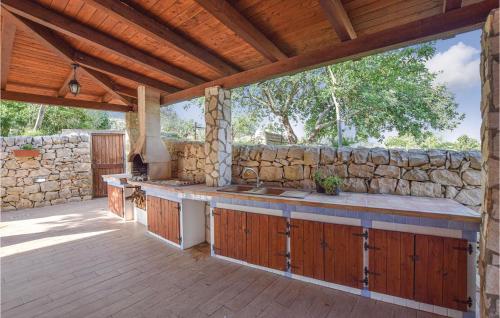 an outdoor kitchen with wooden cabinets and a stone wall at 4 Bedroom Stunning Home In Giarratana in Giarratana