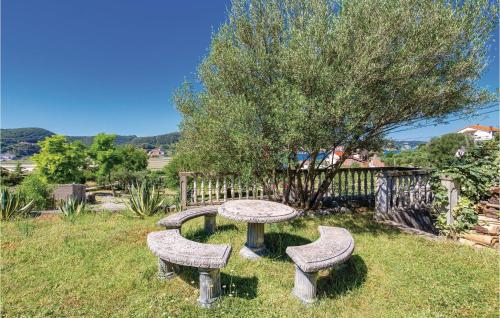 a picnic table and two benches in the grass at Lovely Home In Supetarska Draga in Supetarska Draga