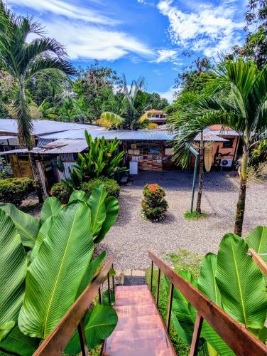 a garden with palm trees and a building at Arboura Eco Cabins in Uvita