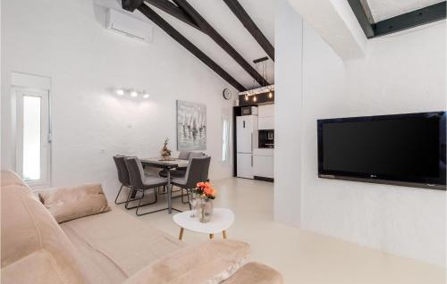 a living room with a couch and a tv and a table at Nice Home In Lopar With Jacuzzi in Lopar