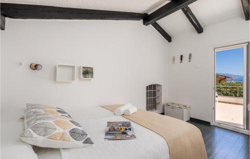 a white bedroom with a bed and a large window at Nice Home In Lopar With Jacuzzi in Lopar