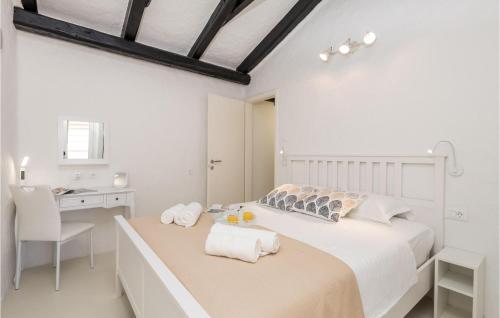 a white bedroom with a bed and a desk at Nice Home In Lopar With Jacuzzi in Lopar