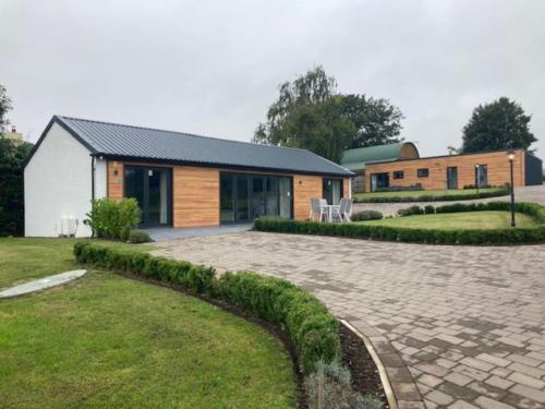 a house with a stone driveway in front of a building at Purpose built 3 bedroom holiday barn in Bonvilston