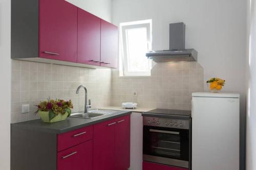 a kitchen with red cabinets and a white refrigerator at Dubravka apartmani in Mokošica