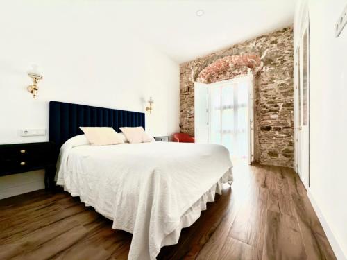 a bedroom with a bed and a brick wall at Suites Plaza Alta in Algeciras