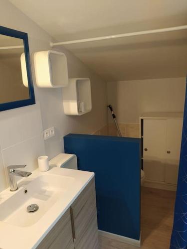 La salle de bains est pourvue d'un lavabo blanc et d'un mur bleu. dans l'établissement appartement neuf au calme, à Sainte-Croix