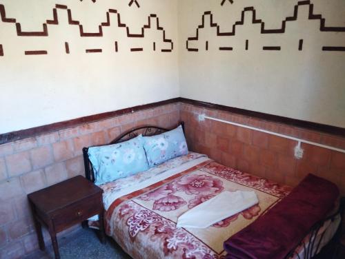 a small room with a bed and a bench at Auberge Restaurant Rooftop Tamazirt in Boumalne