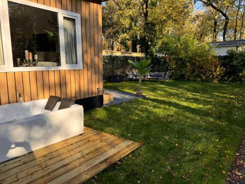 a bath tub sitting on a deck next to a yard at VELUWSHOF HOENDERLOO HOLIDAYS Luxe Holidayhomes with PRIVATE JACUZZI'S - SwimmingPool - Tennis Court - Bowling - Supermarket and Children Entertainment in Hoenderloo