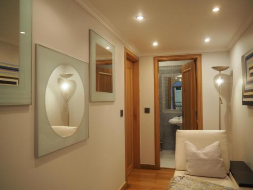 a living room with a white chair and a mirror at Camacho Residence in Funchal