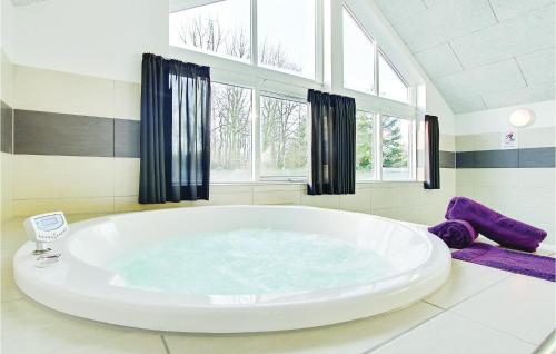 a large white tub in a bathroom with windows at 6 Bedroom Beautiful Home In Tranekær in Hou