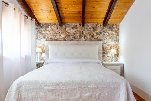 una camera da letto con un letto bianco e un muro di pietra di La Pedrera a Beceite