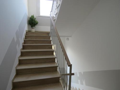 a stairway with a wooden railing and a plant at Hotel Marta in Forlì