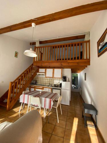 a kitchen and dining room with a table and a staircase at Maison à 800m de la plage classée 1 étoile in Capbreton