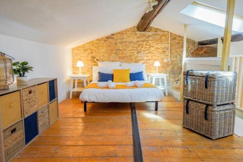 une chambre avec un lit et un mur en pierre dans l'établissement Le Charmant, Calme, Central et Climatisé !, à Nîmes