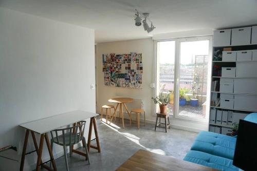un salon avec une table et des chaises et une fenêtre dans l'établissement Studio SUNSET TERRASSE !, à Bordeaux