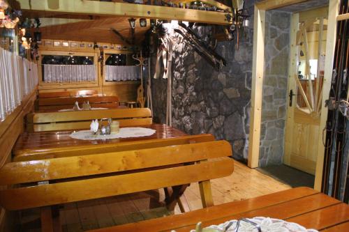 a restaurant with wooden tables and benches and a stone wall at Rusałka in Zakopane