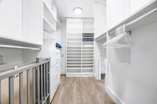 a walk in closet with white cabinets and wood floors at Spectacular Miami 12 mil to Downtown 5Bedrooms Game Room Heated Pool in Tamiami