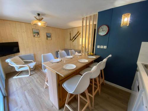 une salle à manger avec une table en bois et des chaises blanches dans l'établissement Appartement T3 Saint Lary Soulan, à Vignec