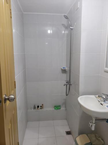 a white bathroom with a shower and a sink at Oceanview 2-bedroom Condo Unit in Dumaguete