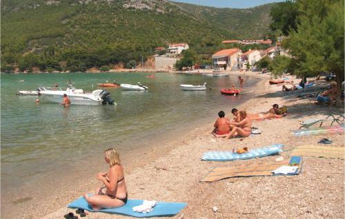 a group of people sitting on the shore of a beach at Holiday Home Zuljana With Sea View I in Žuljana