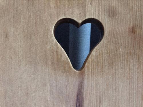 a black heart cut out of a wooden surface at Grüezi Laax Apartments in Laax
