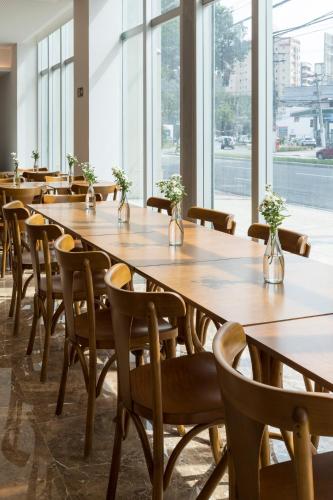 a row of tables and chairs in a room with windows at Sleep Inn Praia do Canto in Vitória