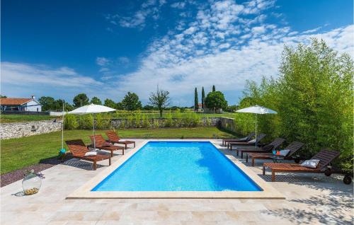 a swimming pool with chairs and umbrellas in a yard at Villa Nino in Rovinj