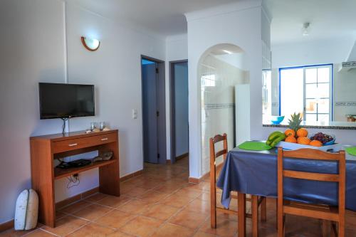 a living room with a table and a television at Casas do Zé in Odeceixe