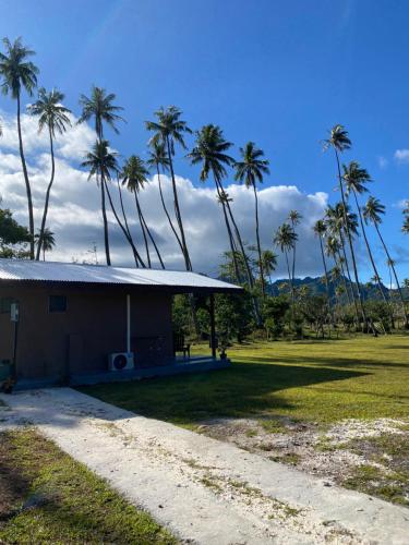 a small house with palm trees in a field at Huahine Serenity Cottage in Maroe