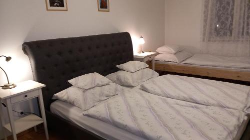 ein Schlafzimmer mit zwei Betten mit weißen Laken und Kissen in der Unterkunft Fűrészmalom vendégház in Matrakeresztes
