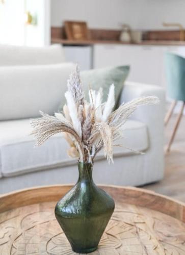 a green vase with white flowers on a table at NUXIA Suites&SPA L'Abohème Chic in Bagnols-sur-Cèze