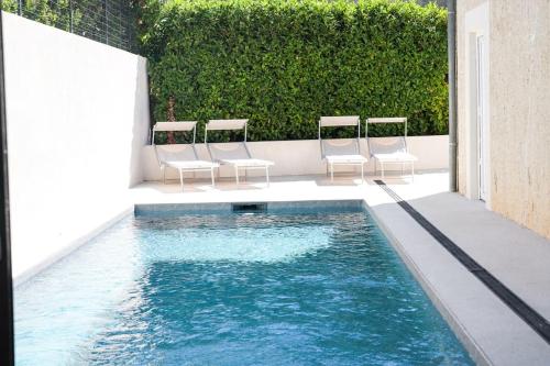 a swimming pool with four chairs and a group of water at NUXIA Suites&SPA L'Abohème Chic in Bagnols-sur-Cèze
