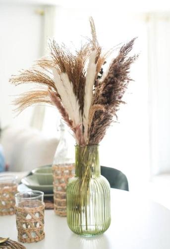 a green vase with feathers in it on a table at NUXIA Suites&SPA L'Abohème Chic in Bagnols-sur-Cèze