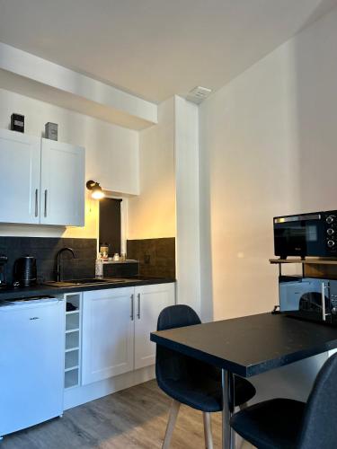une cuisine avec des armoires blanches et une table et des chaises dans l'établissement Le Central - Hypercentre, à Clermont-Ferrand