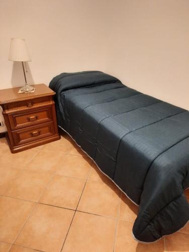 a bed with a blue blanket next to a table at Casa vacanze le coccinelle in Nizza Monferrato